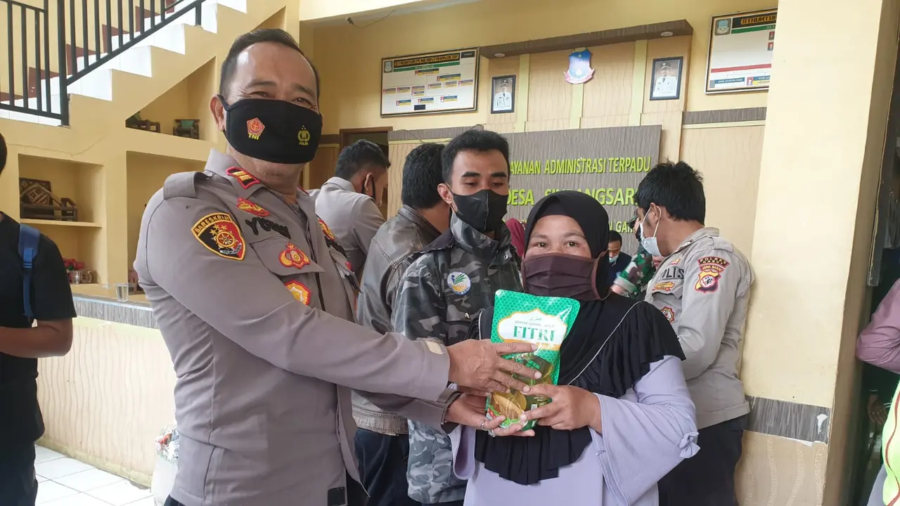 Kapolsek Bayongbong, Inspektur Satu Yusli. Y, tengah memberikan paket minyak goreng di sela-sela vaksinasi Coviud-19 di Desa Sindangsari, Kecamatan Cigedug, Garut, Sabtu (5/2/2022).
