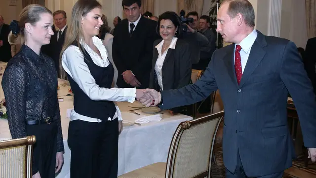 Presiden Rusia Vladimir Putin (kanan) berjabat tangan dengan pesenam Rusia Alina Kabayeva (tengah) dan Svetlana Khorkina (kiri) selama pertemuan dengan para olahragawan, kandidat tim Olimpiade Rusia untuk Olimpiade 2004, di kediaman presiden di Novo-Ogary