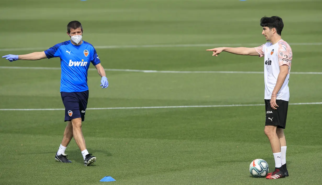 Pelatih Valencia, Albert Celades, memberikan arahan kepada Carlos Soler saat sesi latihan di Paterna Sports City, Paterna, Minggu (10/5/2020). Sejumlah klub di Spanyol memulai latihan seiring rencana akan kembali bergulirnya kompetisi La Liga musim ini. (AFP/Valencia CF/Lazaro De La Pena)