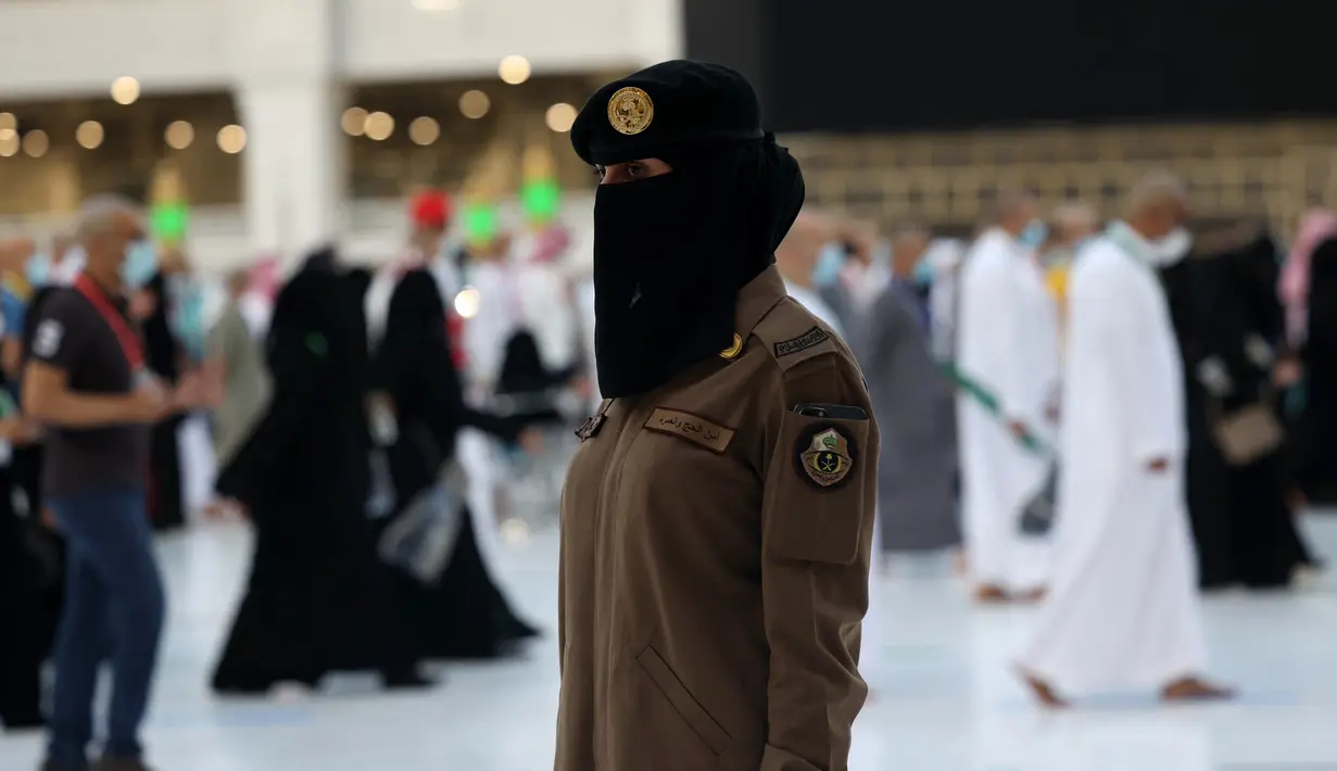 Seorang polisi wanita Saudi berjaga-jaga saat jemaah mengelilingi Ka'bah pada rangkaian ibadah haji di Masjidil Haram, Makkah, Selasa (20/7/2021). Kini, para personel perempuan bergabung dengan rekan-rekan pria mereka dalam menjaga kota suci selama musim haji. (Fayez Nureldine / AFP)