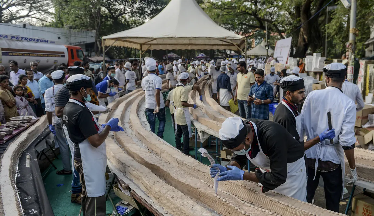 Suasana pembuatan kue sepanjang 6,5 km untuk kue terpanjang dunia, di Thrissur di negara bagian Kerala, India selatan (15/1/2020). Sebelumnya rekor Guinness World Record untuk kue terpanjang diraih di China degan panjang 3,2 kilometer. (AFP/Arun Sankar)
