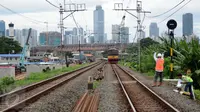 Kereta milintas di dekat proyek pembangunan jalur dua rel ganda atau double-double track (DDT) Manggarai-Cikarang, Jakarta, Jumat (13/1). Menhub mengungkapkan, kendala proyek DDT ini adalah administrasi pembebasan lahan. (Liputan6.com/Gempur M Surya)