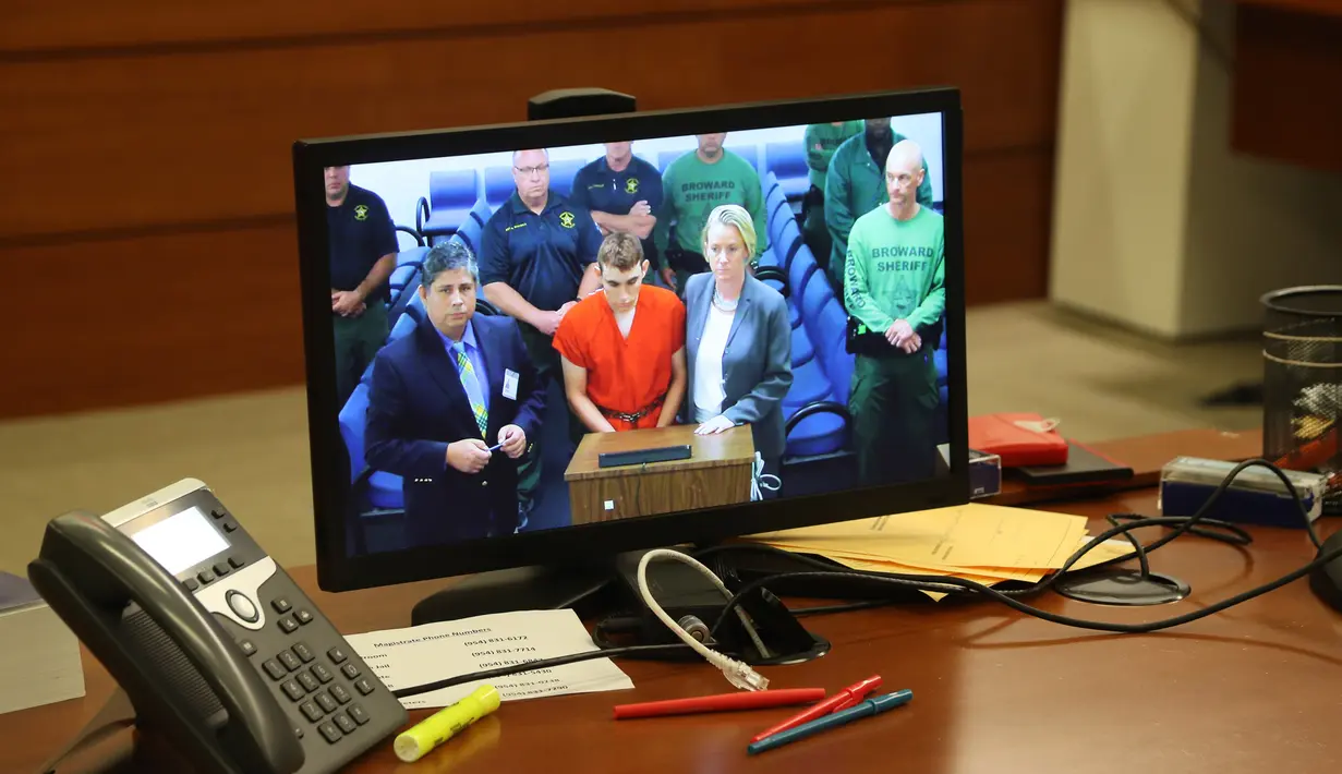 Layar TV menampilkan berita terkait pelaku penembakan massal di Florida yang dilakukan Nikolas Cruz, Florida (15/2). Menurut temannya, Cruz sering mengatakan candaan kasar mengenai keinginannya untuk membunuh dan memiliki senjata. (Susan Stocker/POOL/AFP)