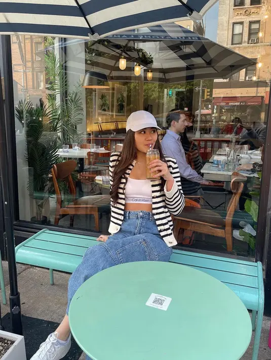 Ngopi ala New Yorker, Aaliyah pilih tampil minimalis dengan sport bra Calvin Klein dan bawahan denim. Striped cardigan dan topi putih jadi pelengkap outfit [@aaliyah.massaid]