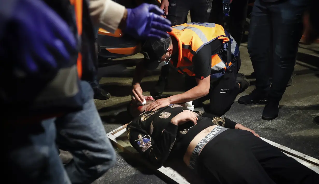Seorang demonstran Palestina yang terluka menerima perawatan setelah dia dipukul dalam bentrokan dengan polisi Israel di Gerbang Damaskus di luar Kota Tua Yerusalem, Kamis (22/4/2021).  Warga Palestina bentrok dengan polisi Israel atas pembatasan pertemuan Ramadhan. (AP Photo/Ariel Schalit)