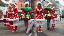 Seorang anak berjalan di depan sejumlah wanita yang mengenakan kostum Santa Claus selama acara mempromosikan musim Natal di sebuah distrik perbelanjaan di Seoul (13/11). (AFP Photo/Jung Yeon-Je)