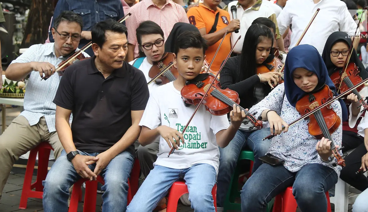 Kepala Kantor Staf Presiden (KSP), Moeldoko melihat komunitas biola memainkan lagu pada perayaan ulang tahunnya yang ke-61 di Taman Suropati, Jakarta, Minggu (8/7). (Liputan6.com/Herman Zakharia)