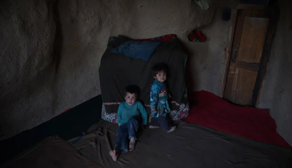 Dua orang anak duduk di dalam gua di kota Bamiyan, Kabul. Foto diambil pada 19 Juni 2015. Ratusan warga miskin Afghanistan terpaksa menghuni gua-gua tersebut untuk dijadikan rumah karena tak memiliki tempat tinggal. (AFP PHOTO / SHAH Marai)