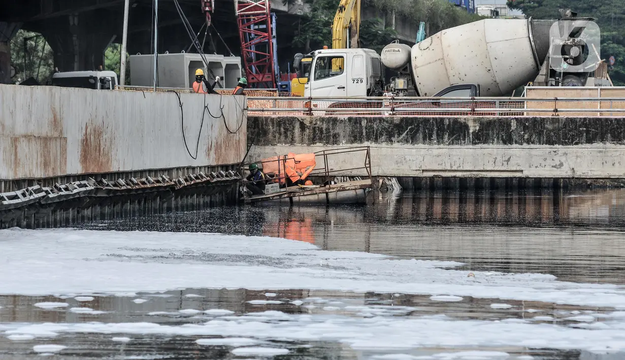 Aktivitas pekerja dekat limbah busa yang mencemari Kali Ancol, Jakarta Utara, Rabu (16/3/2022). Munculnya busa tersebut diduga berasal dari limbah rumah tangga dan industri akibat belum efektifnya Instalasi Pengolahan Air Limbah (IPAL). (merdeka.com/Iqbal S. Nugroho)