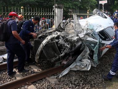Petugas mengevakuasi mobil Honda Mobilio yang tertabrak KRL Commuterline KA 1077 (Bogor-Jakarta Kota) di kawasan Rawageni, Ratu Jaya, Cipayung, Depok, Jawa Barat, Rabu (20/4/2022). Kecelakaan yang terjadi di perlintasan sebidang itu menyebabkan terganggunya perjalanan KRL. (merdeka.com/Arie Basuki)