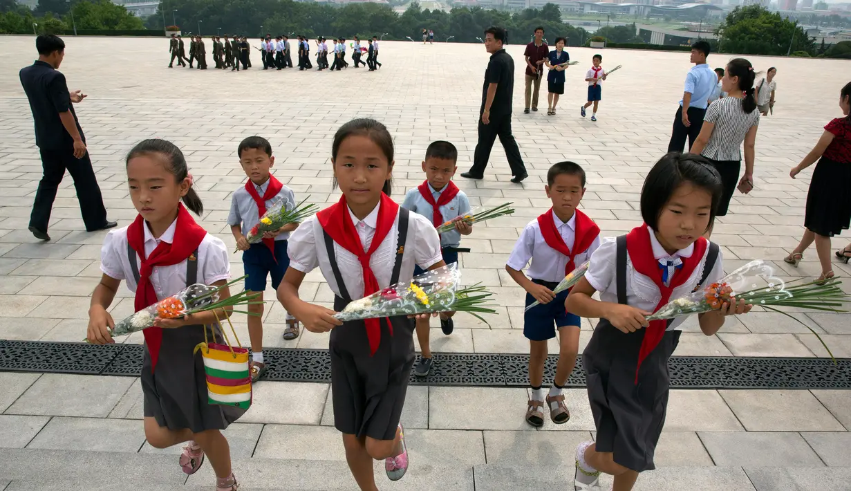 Anak-anak membawa bunga saat akan memberi penghormatan kepada patung pemimpin Korea Utara Kim Il Sung dan Kim Jong Il dalam peringatan berakhirnya Perang Dunia II dan pembebasan dari kolonial Jepang di Pyongyang, Korut, Rabu (15/8). (AP Photo/Ng Han Guan)