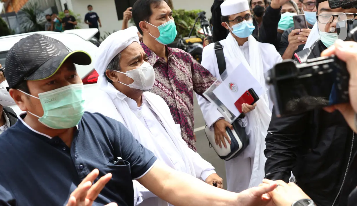 Rizieq Shihab (kedua kiri) sesaat tiba di Mapolda Metro Jaya, Jakarta, Sabtu (12/12/2020). Rizieq Shihab akan menjalani pemeriksan sebagai tersangka penghasutan dan kerumunan di tengah pandemi Covid-19. (Liputan6.com/Helmi Fithriansyah)