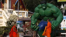 Dua orang biksu berpose di dekat patung "Hulk" di kuil Tamru di Samut Prakan, Thailand (3/3). Pihak Candi mengatakan telah menyiapkan patung-patung karakter komik Marvel untuk menarik pengunjung. (REUTERS/Chaiwat Subprasom)