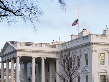 Bendera Amerika tampak berkibar setengah tiang untuk menandai 500.000 kematian akibat Covid-19 di Gedung Putih di Washington D.C. pada Senin (22/2/2021). Presiden Joe Biden memerintahkan agar bendera AS di properti federal diturunkan menjadi setengah tiang selama lima hari. (SAUL LOEB/AFP)