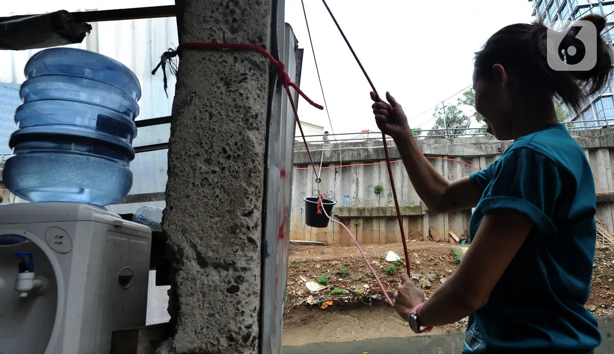Pemilik warung menarik ember saat melayani pembeli di seberang Kali Mampang, Mampang Prapatan, Jakarta Selatan. (merdeka.com/Arie Basuki)