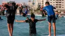 Anak-anak Palestina bermain di air mancur umum selama hari musim panas di Kota Gaza (20/7/2020). Musim panas yang terjadi di Palestina membuat anak-anak memenuhi air mancur. Mereka berupaya mendinginkan tubuh mereka dengan cara berenang di air mancur tersebut. (AFP Photo/Mahmud Hams)