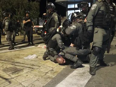Petugas polisi perbatasan Israel menahan seorang demonstran Palestina saat bentrokan dengan pengunjuk rasa Palestina, di Yerusalem timur, Jumat (7/6/2021).  Warga Palestina memprotes atas ancaman penggusuran Israel atas puluhan warga Palestina di lingkungan Sheikh Jarrah. (AP Photo/Mahmoud Illean)