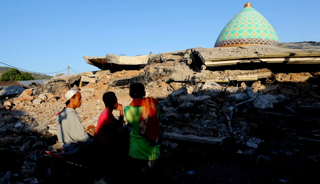 Warga melihat reruntuhan bangunan Masjid Jamiul Jamaah yang rusak akibat gempa bumi di Bangsal, Lombok Utara, Rabu (8/8). Berdasarkan kesaksian warga, diduga puluhan korban yang sedang melaksanakan pengajian tertimbun bangunan masjid. (AP/Tatan Syuflana)