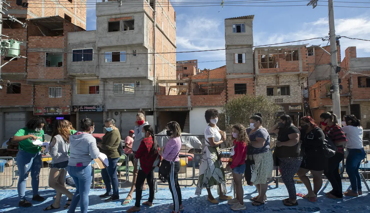Sejumlah wanita dan anak-anak mengantre untuk menerima sumbangan pembalut wanita dan perlengkapan kebersihan lainnya di tengah pandemi COVID-19 di favela Paraisopolis, di Sao Paulo, Brasil (24/5/2021). Sumbangan ini disediakan oleh LSM lokal "G10 Favelas". (AP Photo/Andre Penner)