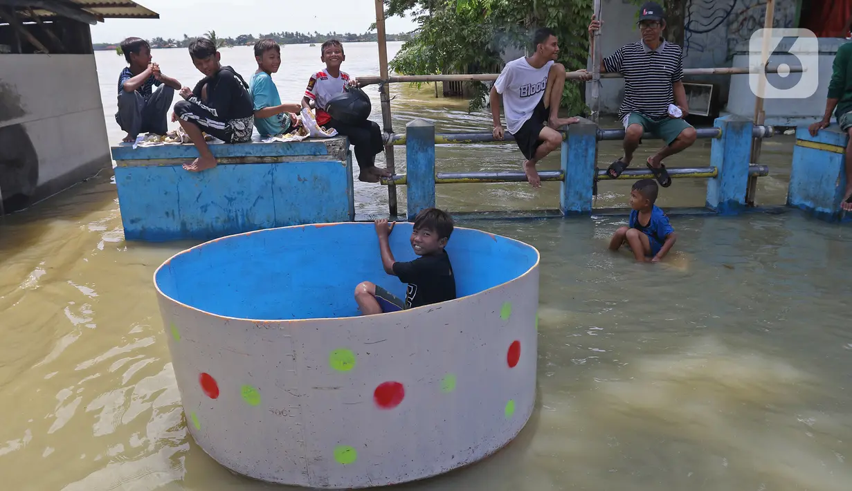 Anak-anak duduk di jembatan saat banjir di Desa Sukalaksana Kabupaten Bekasi, Jawa Barat, Senin (22/02/2021). Hujan dengan intensitas tinggi turun sejak Jumat, 19 Februari 2021 mengakibatkan air di aliran sungai meluap. (Liputan6.com/Herman Zakharia)