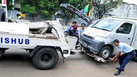 Petugas Dinas Perhubungan DKI Jakarta memasang alat derek untuk membawa mobil yang parkir di bahu jalan di kawasan Jatinegara, Jakarta, Senin (2/10). (Liputan6.com/Helmi Afandi)