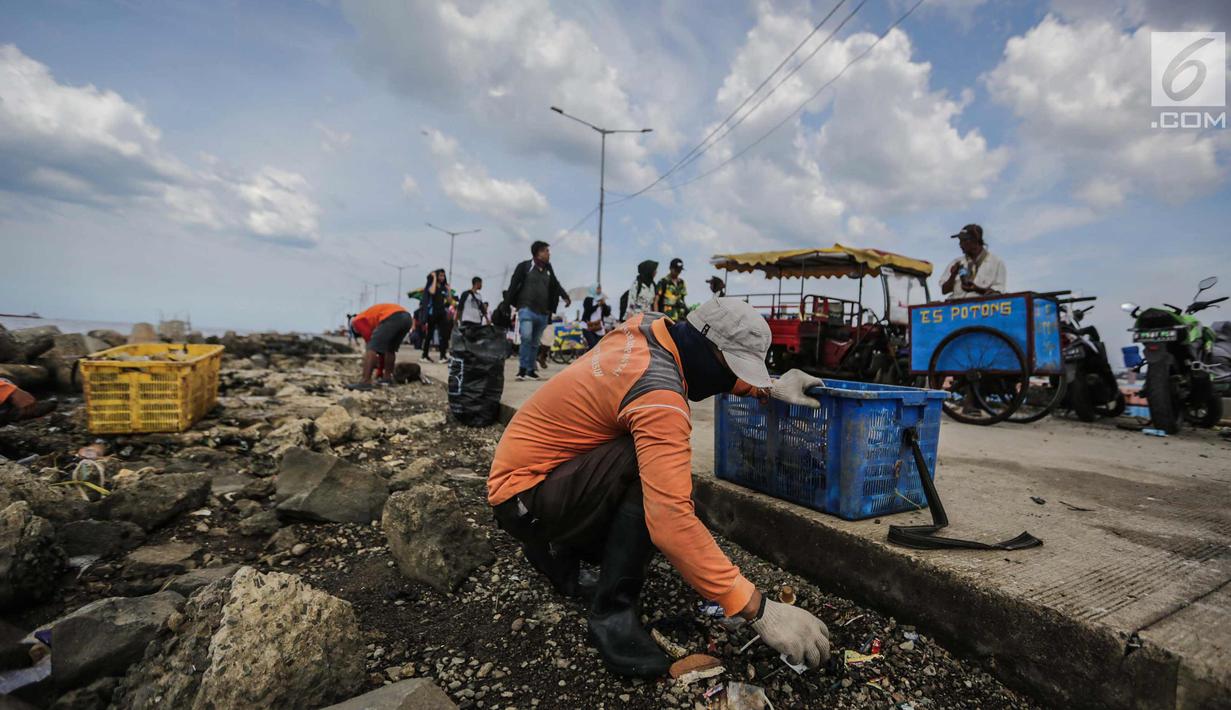 Petugas kebersihan membersihkan sampah laut di Pelabuhan Kali Adem, Jakarta, Senin (1/1). Banyaknya sampah plastik dibandingkan ikan yang gagal dikelola dengan baik membuat limbah yang mengakibatkan laut tercemar.  (Liputan6.com/Faizal Fanani)
