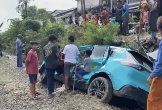 Taksi Green SM yang tertemper oleh KRL di perlintasan sebidang di jalan Ampera, Kota Bekasi, jadi tontonan warga sekitar. (Foto: Liputan6.com/Rifqy Alief Abiyya).