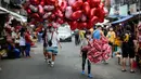 Penjual balon berbentuk hati menjajakan dagangannya di pasar bunga di Manila, Filipina, Senin (13/2/2023). Harga bunga naik karena tingginya permintaan sehari sebelum Hari Valentine. (AP Photo/Aaron Favila)