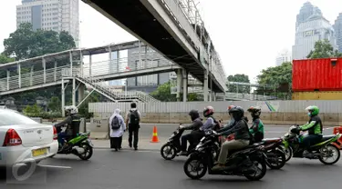 Sejumlah warga nekat menyeberang di bawah JPO sisi barat Polda Metro Jaya di Jalan Jenderal Sudirman, Jakarta, yang ditutup dan dibongkar, Senin (23/11). Pembongkaran dilakukan karena adanya perbaikan saluran air. (Liputan6.com/Yoppy Renato)