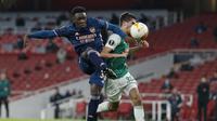 Striker Arsenal, Folarin Balogun (kiri), melepaskan tendangan dibawah tekanan bek Rapid Wien, Leo Greiml, dalam laga lanjutan Liga Europa 2020/21 Grup B di Emirates Stadium, Kamis (3/12/2020) waktu setempat. Arsenal mengalahkan Rapid Wien 4-1. (AFP/Adrian Dennis)