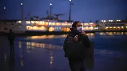 Seorang pria menyesuaikan masker pelindungnya untuk mencegah penyebaran COVID-19 saat dia berjalan di terminal feri Karakoy di Istanbul, Turki  (11/1/2022). Meskipun ada lonjakan, negara tersebut belum mempertimbangkan untuk memberlakukan pembatasan baru. (AP Photo/Francisco Seco)