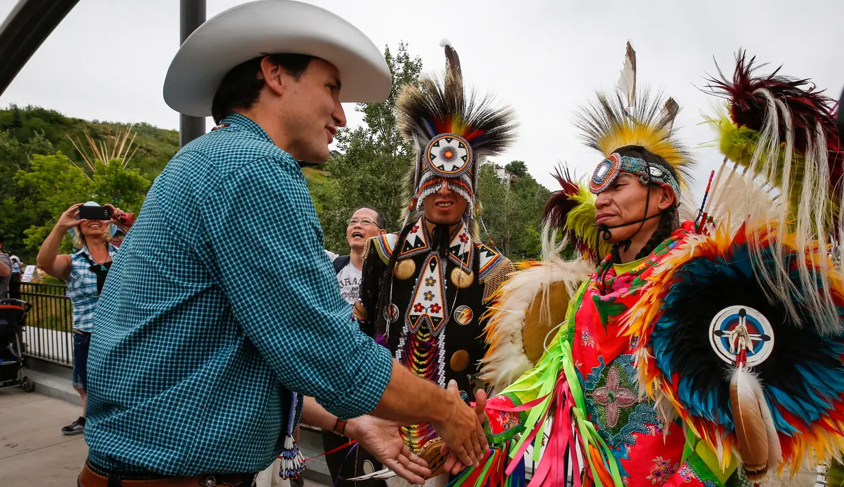 Perdana Menteri Kanada Justin Trudeau bersalaman dengan penari pribumi setempat dalam acara Calgary Stampede di Calgary, Alberta, Kanada (15/7). Festival dan pameran ini diadakan setiap bulan Juli di Calgary. (Jeff McIntosh / The Canadian Press via AP)
