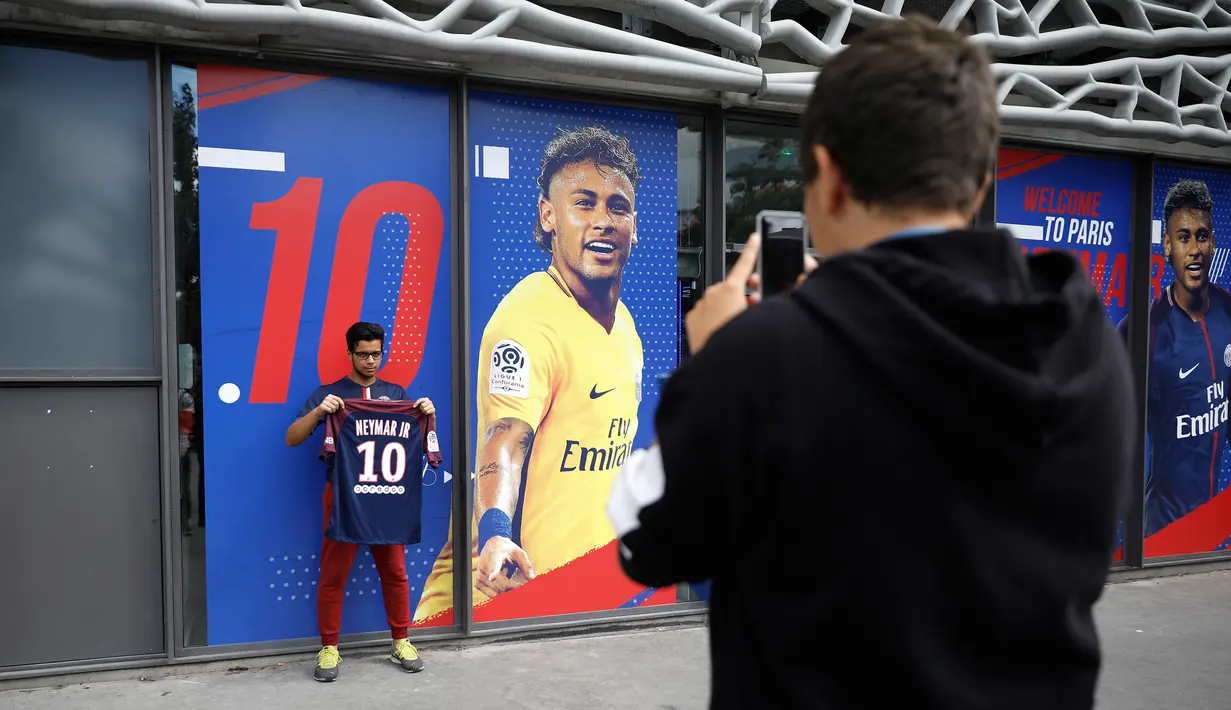 uporter berpose dengan jersey Neymar Jr di depan toko Paris Saint Germain di Paris (4/8). Setelah diumumkan PSG, toko-toko merchandise mulai menjual jersey eks pemain Barcelona tersebut. (AP Photo/Michel Euler)