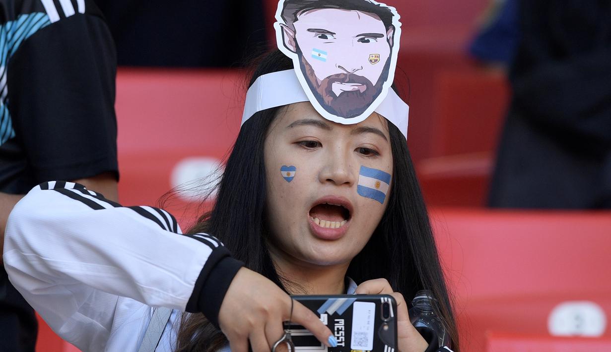 Suporter cantik menggunakan topeng Messi saat menyaksikan laga Argentina melawan Islandia pada Piala Dunia 2018 di Spartak Stadium, Moskow, (16/6/ 2018). Argentina dan Islandia bermain imbang 1-1. (AFP/Juan Mabromata)