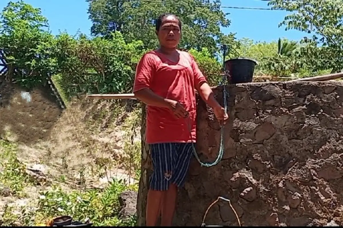 Maria Veneranda, sedang menimba air di bak penampungan air miliknya yang dibelih dari mobl tangki. (Liputan6.com/Dionisius Wilibardus)