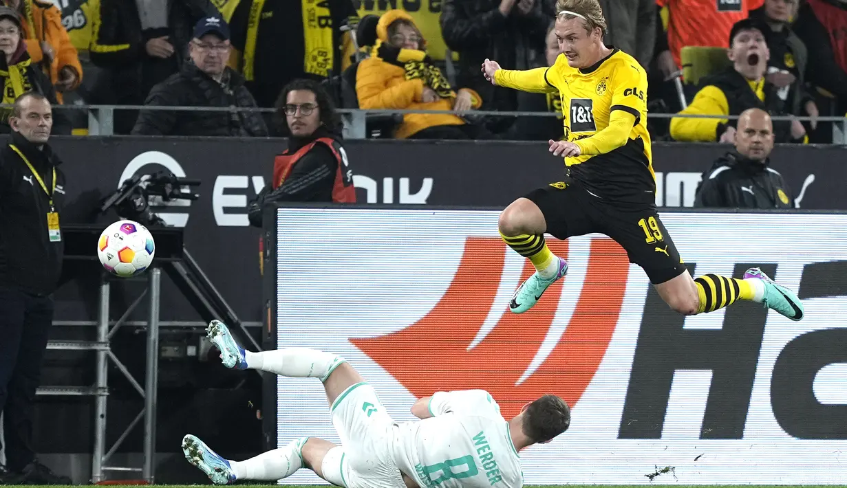 Gelandang Borussia Dortmund Julian Brandt berebut bola dengan bek Werder Bremen Mitchell Weiser dalam laga Bundesliga 2023/2024 pekan 8 yang digelar di Signal Iduna Park, Sabtu (21/10/2023) dini hari WIB. (AP Photo/Martin Meissner)