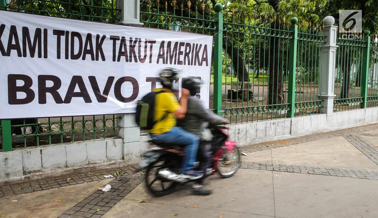Kendaraan melintas di depan spanduk bertulisan "Kami Tidak Takut Amerika Bravo TNI" terpampang di pagar Stasiun Gambir, Jakarta, Senin (23/10). Pemasangan spanduk ini diduga terkait undangan Panglima TNI yang ditolak masuk AS. (Liputan6.com/Faizal Fanani)