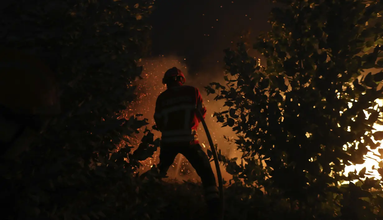 Seorang petugas pemadam kebakaran berusaha memadamkan kebakaran hutan di daerah Rio Maior di Portugal, Rabu (17/8/2022). Pihak berwenang di Portugal mengatakan mereka berharap untuk mengendalikan api yang telah membakar selama 12 hari dan membakar petak besar hutan pinus di Taman Alam Serra da Estrela. (AP Photo/Joao Henriques)