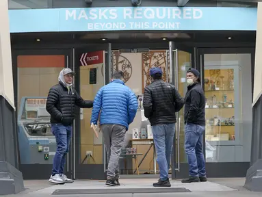 Orang-orang berjalan ke pintu masuk di Space Needle di bawah tanda bertuliskan "Masker Diperlukan" di Seattle pada 17 Februari 2022. Gubernur Jay Inslee mengatakan mandat masker dalam ruangan di negara bagian Washington akan dicabut pada 21 Maret 2022 mendatang. (AP Photo/Ted S. Warren)