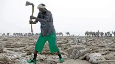 Seorang pria mencangkul di tambang garam di Danakil Depression, Afar, Ethiopia (28/3). Penduduk Ethiopia banyak yang menggantungkan hidup mereka sebagai penambang garam. (AFP Photo/Zacharias Abubeker)