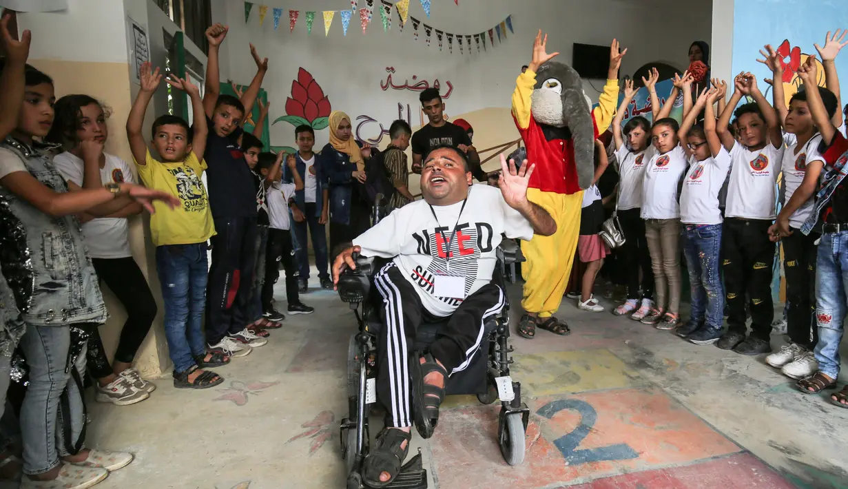 Nihad Jarboa (37) dikelilingi oleh anak-anak dan relawan, salah satunya mengenakan kostum yang dibuat oleh dia dan istrinya Zeinab, di sebuah pusat anak-anak dengan penyakit kronis di kamp pengungsi Rafah di Jalur Gaza selatan, pada 21 Juli 2020. (AFP Photo/Said Khatib)