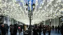 Sejumlah pejalan kaki melintas di bawah dekorasi lampu yang menghiasi sebuah jalan pusat kota Moskow, Senin (18/12). Salah satu sudut kota di Rusia itu didekorasi dengan lampu dan pernak-pernik perayaan Natal dan Tahun Baru. (AFP PHOTO / Yuri KADOBNOV)