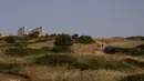 Sepasang pengunjung berjalan menuju Kuil Poseidon di Cape Sounion, Athena, Yunani, Senin (18/5/2020). Yunani kembali membuka kota kuno Acropolis serta situs-situs lainnya setelah dua bulan ditutup selama lockdown akibat pandemi virus corona COVID-19. (AP Photo/Petros Giannakouris)
