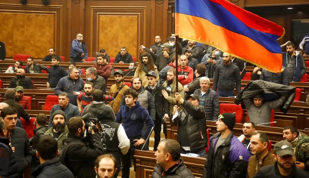 Demonstran membawa bendera Armenia saat memprotes kesepakatan untuk menghentikan pertempuran di Nagorno-Karabakh di Gedung Parlemen, Yerevan, Armenia, Selasa (10/11/2020). PM Armenia Nikol Pashinian menyerukan diakhirinya pertempuran dengan Azerbaijan. (AP Photo/Dmitri Lovetsky)