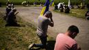 <p>Pelayat berlutut saat mereka menunggu peti mati Volodymyr Losev (38) untuk lewat saat pemakamannya di Zorya Truda, wilayah Odesa, Ukraina, Senin, 16 Mei 2022. Volodymyr Losev, seorang tentara relawan Ukraina, tewas pada 7 Mei lalu ketika kendaraan militer yang dikendarainya menabrak sebuah ranjau di Ukraina timur. (AP Photo/Francisco Seco)</p>
