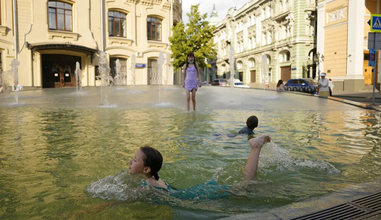Anak-anak bermain air mancur di pusat kota Moskow, Rusia, Rabu (14/7/2021). Cuaca panas di Moskow berlanjut dengan suhu mencapai 34 derajat Celcius (93,2 Fahrenheit) dalam sehari. (AP Photo/Pavel Golovkin)