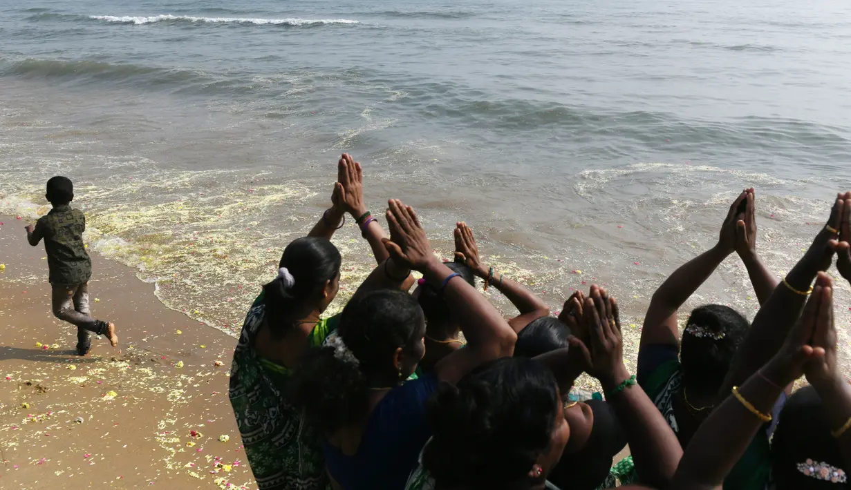 Para wanita memanjatkan doa saat melarung bunga persembahan dalam upacara penghormatan untuk korban tsunami Samudra Hindia tahun 2004 di Pantai Pattinapakkam, Chennai, India, Rabu (26/12). (ARUN SANKAR/AFP)