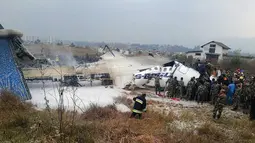 Suasana saat tim penyelamat berkumpul di sekitar puing pesawat yang jatuh di dekat Bandara Internasional Kathmandu, Nepal, Senin (12/3). Sebanyak 40 orang tewas dan 23 lainnya cedera. (Saroj BASNET/AFP)