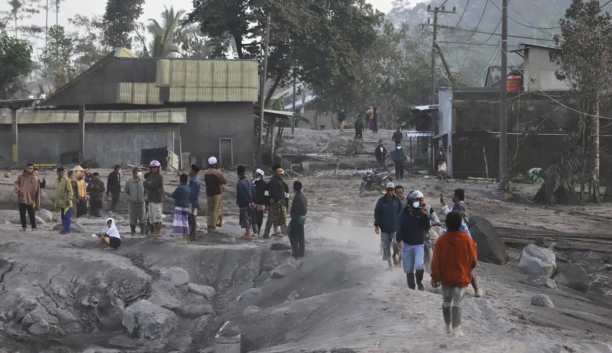Orang-orang memeriksa desa mereka yang tertutup abu setelah letusan Gunung Semeru di Lumajang, Jawa Timur, Indonesia, Senin, 5 Desember 2022. Petugas Pos Pengamatan Gunung Api (PPGA) Semeru, Mukdas Sofian mengatakan, aktivitas Gunung Semeru pada periode pengamatan 5 Desember 2022 pukul 00.00-06.00 WIB mengalami satu kali awan panas guguran dengan amplitudo 25 mm dan lama gempa 386 detik. (AP Photo/Imanuel Yoga)
