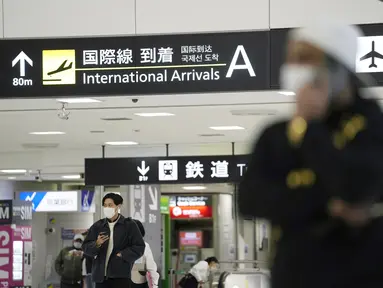 Pria memegang ponsel saat berdiri di terminal kedatangan internasional di Bandara Narita, timur Tokyo, Kamis (2/12/2021). Maskapai-maskapai internasional diminta menangguhkan reservasi baru pada semua penerbangan masuk ke Jepang hingga akhir Desember terkait varian Omicron. (AP Photo/Hiro Komae)